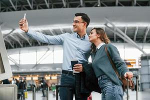 haciendo selfie pareja joven está en el aeropuerto juntos foto