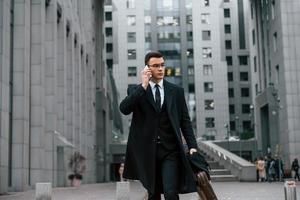 ropa informal. hombre de negocios con traje negro y corbata está al aire libre en la ciudad foto