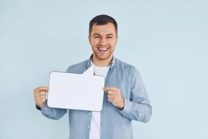 Smiling and having good mood. Man standing in the studio with empty signs for the text photo