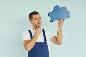 In blue uniform. Man standing in the studio with empty signs for the text photo