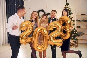 2023 balloons in hands. Group of people have a new year party indoors together photo