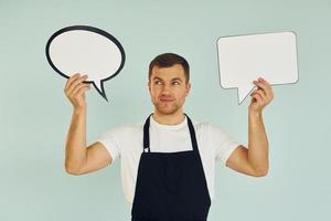 Hard choice between two ideas. Man standing in the studio with empty signs for the text photo
