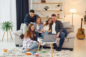 Using laptop. Group of friends have party indoors together photo