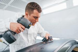 Working with car surface. Man in uniform is working in the auto service photo