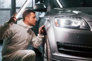 Process of painting the car. Man in uniform is working in the auto service photo