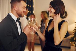 Cheerful couple. Group of people have a new year party indoors together photo