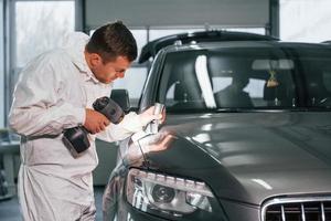 usando equipo especial. el hombre de uniforme está trabajando en el servicio de automóviles foto