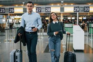 caminando hacia adelante pareja joven está en el aeropuerto juntos foto