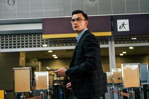 Modern background. Young businessman in formal clothes is in the airport at daytime photo