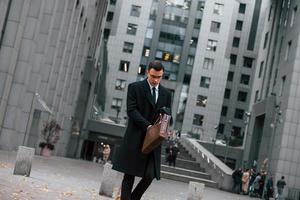 In formal clothes. Businessman in black suit and tie is outdoors in the city photo