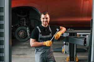 servicio profesional. el hombre de uniforme está trabajando en el servicio de automóviles foto