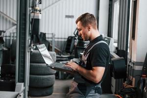 Man in uniform is working in the auto service photo