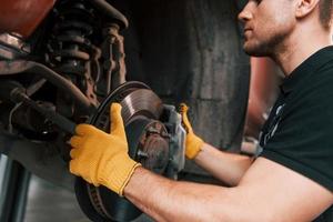 Fixing breaks. Man in uniform is working in the auto service photo