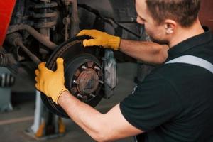 Fixing breaks. Man in uniform is working in the auto service photo