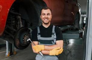 Standing with arms crossed. Man in uniform is working in the auto service photo