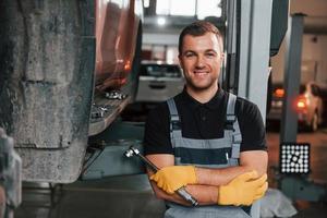 Standing with arms crossed. Man in uniform is working in the auto service photo