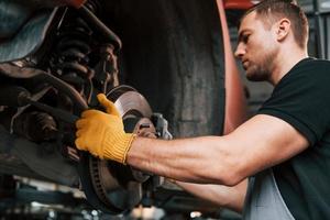Fixing breaks. Man in uniform is working in the auto service photo