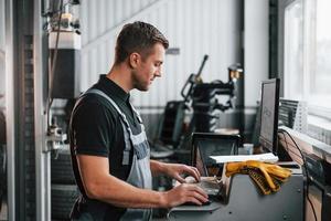 Professional service. Man in uniform is working in the auto service photo