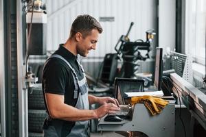At daytime. Man in uniform is working in the auto service photo