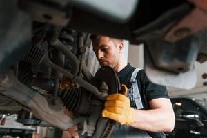 Professional service. Man in uniform is working in the auto service photo