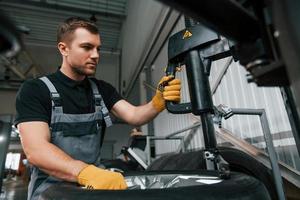 manos fuertes. el hombre de uniforme está trabajando en el servicio de automóviles foto