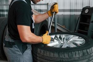 Working with broken wheel. Man in uniform is working in the auto service photo