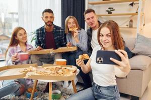 It's pizza time. Group of friends have party indoors together photo