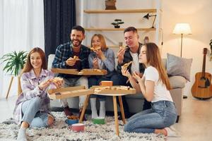 It's pizza time. Group of friends have party indoors together photo