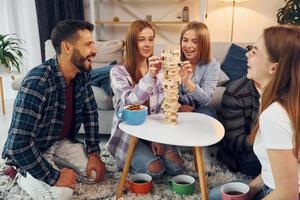 juego de torre de madera sobre la mesa. grupo de amigos tienen una fiesta en el interior juntos foto