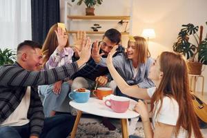 divirtiéndose. grupo de amigos tienen una fiesta en el interior juntos foto