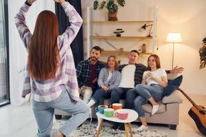 Playing game with using body language and poses. Group of friends have party indoors together photo