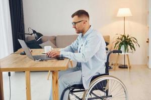 Smart freelance worker. Disabled man in wheelchair is at home photo