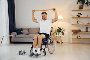 Stretching the hands. Disabled man in wheelchair is at home photo