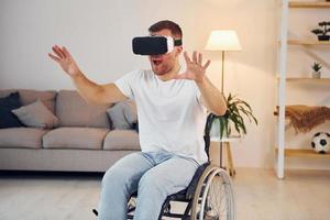 In VR glasses. Disabled man in wheelchair is at home photo