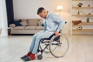 Trying to stand up. Disabled man in wheelchair is at home photo