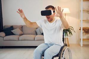 In VR glasses. Disabled man in wheelchair is at home photo