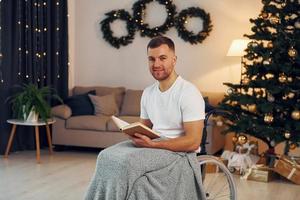 Reading the book. New year is coming. Disabled man in wheelchair is at home photo