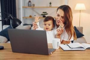 viendo películas usando una computadora portátil. madre con su pequeña hija está en casa juntos foto