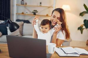 viendo películas usando una computadora portátil. madre con su pequeña hija está en casa juntos foto