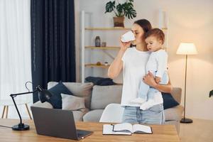 Using laptop. Mother with her little daughter is at home together photo