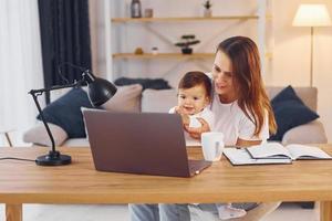 viendo películas usando una computadora portátil. madre con su pequeña hija está en casa juntos foto