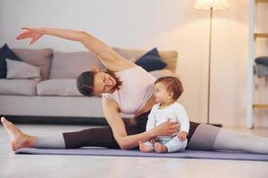 enseñanza de la aptitud física. madre con su pequeña hija está en casa juntos foto