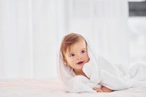 With white towel. Cute little baby is indoors in the domestic room photo