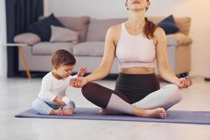 enfocado en ejercicios de yoga. madre con su pequeña hija está en casa juntos foto