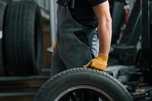 Replacement of the old tire. Man in uniform is working in the auto service photo