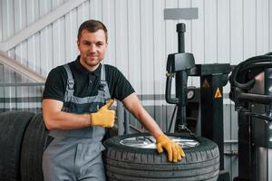 Broken wheel. Man in uniform is working in the auto service photo