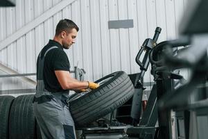 Walking and holding tyre. Man in uniform is working in the auto service photo