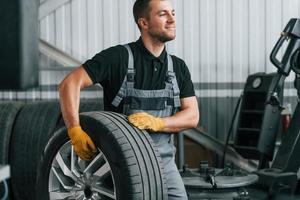 In uniform. Man is working in the auto service photo