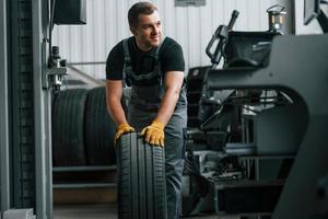 In uniform. Man is working in the auto service photo