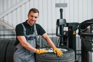 Broken wheel. Man in uniform is working in the auto service photo